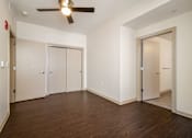 Thumbnail 6 of 16 - A room with a ceiling fan and wooden floors.