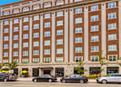 Thumbnail 16 of 16 - A large red brick building with a parking lot in front.
