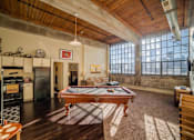 Thumbnail 27 of 41 - A billiard table is in the middle of a room with a wooden floor and a large window.
