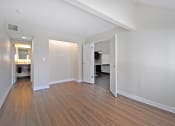 Thumbnail 19 of 32 - a spacious living room with wood flooring and a door to a kitchen