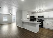 Thumbnail 4 of 24 - A kitchen with white cabinets and a black countertop.