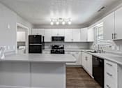 Thumbnail 5 of 24 - A kitchen with white cabinets and a black fridge.