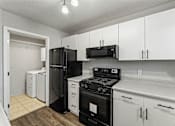 Thumbnail 3 of 24 - A kitchen with black appliances and white cabinets.