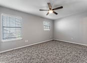 Thumbnail 8 of 24 - A room with a ceiling fan and carpeted floor.