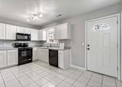 Thumbnail 14 of 24 - A kitchen with white cabinets and black appliances.