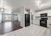 Thumbnail 15 of 24 - A kitchen with black appliances and white cabinets.