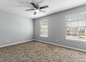 Thumbnail 18 of 24 - A room with a ceiling fan and carpeted floor.