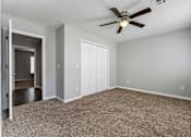 Thumbnail 19 of 24 - A room with a ceiling fan and carpeted floor.