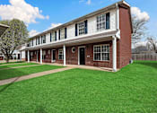Thumbnail 21 of 24 - A red brick building with white trim and a black door.