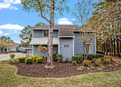 Thumbnail 27 of 32 - A house with a grey siding and a tree in front of it.
