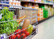 Thumbnail 8 of 11 - A shopping cart filled with vegetables in a grocery store.