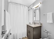 Thumbnail 12 of 44 - A bathroom with a sink, mirror, and shower curtain.