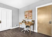 Thumbnail 13 of 44 - A room with a desk and a chair in front of a wooden door.