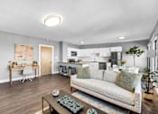 Thumbnail 9 of 44 - A modern living room with a couch, coffee table, and a kitchen in the background.