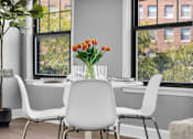 Thumbnail 6 of 44 - A dining table with chairs and a vase of flowers in front of a window.