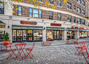 Thumbnail 27 of 44 - A restaurant with red chairs and tables outside.