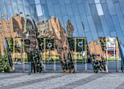 Thumbnail 34 of 44 - A large, modern sculpture made of mirrored panels is reflected in a glass panel.
