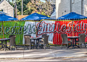 Thumbnail 24 of 44 - A restaurant with blue umbrellas and a sign that says "Welcome to Cville Fay".
