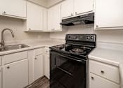 Thumbnail 3 of 15 - A black stove in a kitchen with white cabinets.