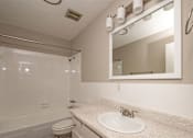 Thumbnail 11 of 15 - A bathroom with a white toilet, sink, and mirror.