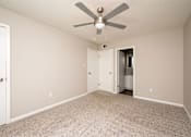 Thumbnail 8 of 15 - A room with a ceiling fan and carpeted floor.