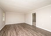 Thumbnail 6 of 15 - A room with a wooden floor and a doorway leading to another room.