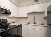 Thumbnail 2 of 15 - A kitchen with white cabinets and a black stove top.