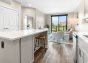 Thumbnail 6 of 82 - a kitchen with white cabinets and a white island with a wooden stool
