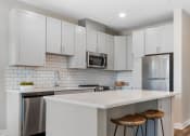 Thumbnail 5 of 82 - a kitchen with white cabinets and a white island with two stools