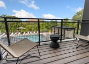 Thumbnail 8 of 82 - a balcony with two chairs and a table and a pool in the background