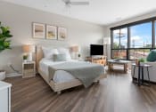 Thumbnail 17 of 82 - a bedroom with a bed and a tv in a room with hardwood floors