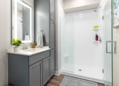Thumbnail 18 of 82 - a bathroom with gray cabinets and a white shower stall