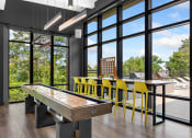 Thumbnail 38 of 82 - a games room with a shuffleboard table and yellow bar stools