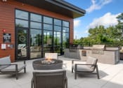 Thumbnail 35 of 82 - a patio with chairs and a fire pit in front of a building with large windows