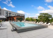 Thumbnail 33 of 82 - a swimming pool with chaise lounge chairs and umbrellas in front of a building
