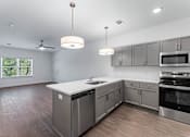Thumbnail 4 of 26 - A modern kitchen with stainless steel appliances and wooden flooring.