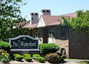 Thumbnail 24 of 24 - A brick building with a sign that says The Waterford in front of it.