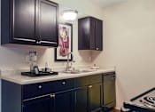 Thumbnail 2 of 24 - A kitchen with black cabinets and a white countertop.