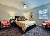Thumbnail 7 of 24 - A bedroom with a bed, two chairs, and a nightstand.