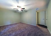 Thumbnail 11 of 24 - A room with a ceiling fan and carpeted floor.