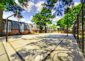 Thumbnail 22 of 24 - A basketball court surrounded by trees and a fence.