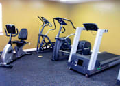 Thumbnail 16 of 24 - A gym with a treadmill, elliptical trainer and a recumbent bike.