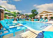 Thumbnail 17 of 24 - A pool area with blue chairs and a white pavilion.