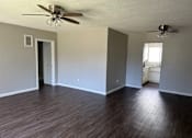 Thumbnail 20 of 35 - an empty living room with wood floors and a ceiling fan