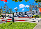 Thumbnail 1 of 29 - A sunny day at the Heritage Apartments with cars parked and trees in the background.