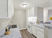 Thumbnail 14 of 27 - Modern kitchen with white appliances and granite countertops at ELEVATE Apartments HOMES, California, 92870