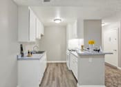 Thumbnail 18 of 27 - Galley kitchen with white appliances and breakfast bar at ELEVATE Apartments HOMES, Placentia, California