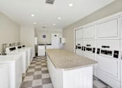 Thumbnail 25 of 27 - Community laundry facility with folding table at ELEVATE Apartments HOMES, Placentia