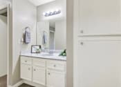 Thumbnail 26 of 27 - Bathroom vanity with white cabinetry and storage at ELEVATE Apartments HOMES, California