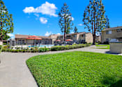 Thumbnail 3 of 27 - Fenced pool area with walking path and greenery at ELEVATE Apartments HOMES, Placentia, CA